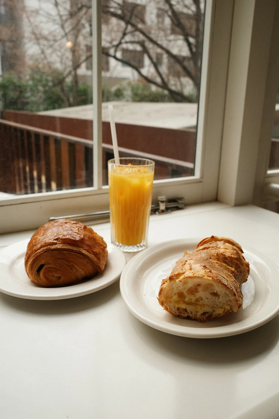 Croissant, toast, juice and drinks on a windowsill