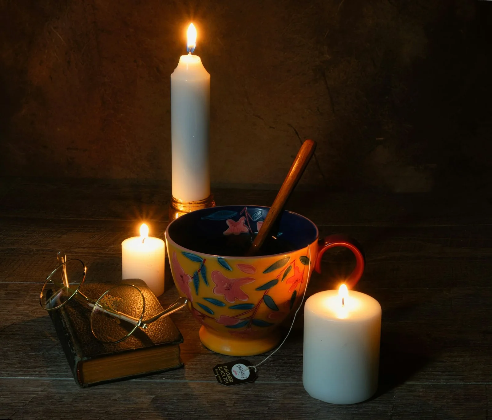Teacup and book illuminated by candles